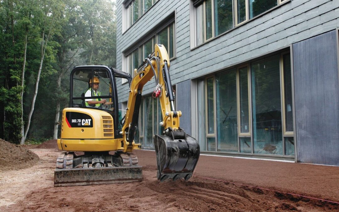 Mini-pelle effectuant un terrassement en bordure d’une maison moderne, exemple de travaux d’étanchéité par l’extérieur